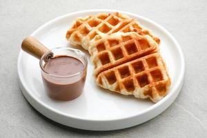 Plain Croissant Waffle or Croffle  with chocolate sauce served in white plate on grey background. Close up. photo