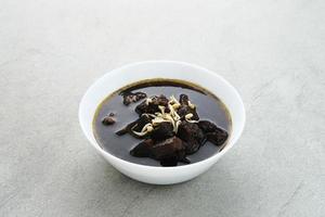 Rawon, Indonesian Traditional beef black soup. Served on a bowl with mung bean sprouts, chilli paste and salted egg photo