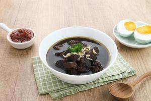 Rawon, Indonesian Traditional beef black soup. Served on a bowl with mung bean sprouts, chilli paste and salted egg photo