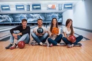 Relaxating together. Young cheerful friends have fun in bowling club at their weekends photo