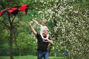 Walking around. Running with red kite. Child sitting on the man's shoulders. Having fun photo