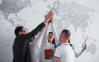 Team of freelancers standing against wall with map of the world on it photo