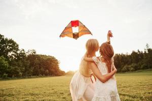 What is that in the sky. Mother and daughter have fun with kite in the field. Beautiful nature photo