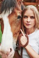 foto vertical. mujer feliz con su caballo en el rancho durante el día