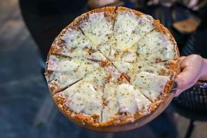 cheesy ham pizza top up with oregano on woman hand., Foodtrack event in Bangkok, Thialand. photo