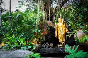 Golden follower Buddha statues walking post on the rock arrounding with plant and vine., Golden Mount, Bangkok, Thailand. photo