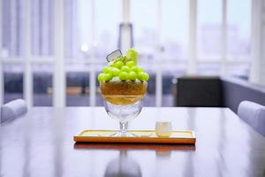 green melon ball shape are arranged on the top of bingsu korean icecream style and decorated with green tea ice-cream and mint leaf on the wood plate and Sweetened condensed milk beside. photo