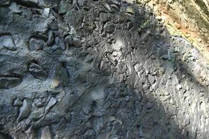 Muro de hormigón pintado de gris con piedras en puntos foto