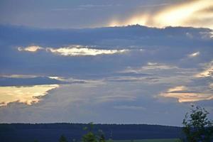 las nubes de la tarde son de color rosa azul y el horizonte del bosque foto