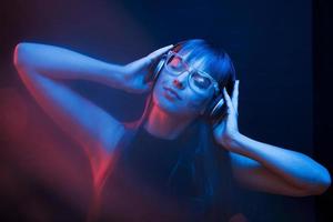 Warm temperature. Studio shot in dark studio with neon light. Portrait of young girl photo