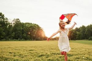 Such a lovely weather today. Happy girl in white clothes have fun with kite in the field. Beautiful nature photo