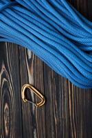 Under long blue knot. Isolated photo of climbing equipment. Part of carabiner lying on the wooden table