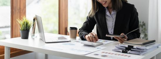 Businesswoman using calculator for analysis maketing plan, Accountant calculate financial report, computer with graph chart. Business, Finance and Accounting concept photo