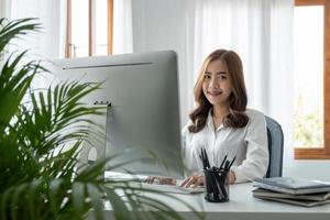 Charming asian woman watching webinar on computer express opinion offer solution at virtual meeting. Student use pc and internet e-learning remotely. photo