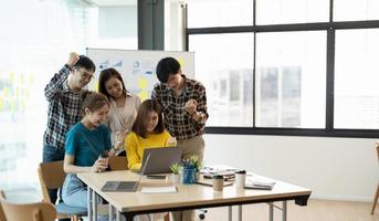 el brazo levantado del logro del éxito del equipo de negocios asiático joven, la cooperación del trabajo en equipo, la formación de equipos o el concepto de proyecto de negocio de éxito foto