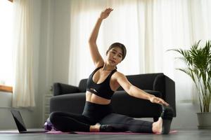 bella joven practicando yoga viendo videos en una laptop en casa - fitness, concepto de entrenamiento foto