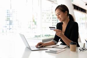 Close up of black girl hold bank credit card and type on laptop, shopping online using computer, buying goods or ordering online, entering bank accounts and details in online banking offer photo