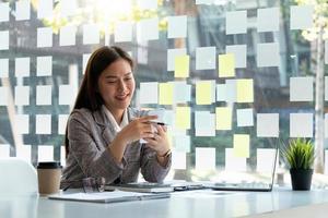 mujer de negocios que usa teléfono móvil y computadora laprop para calcular el informe financiero y llamar al banquero para consultar. foto