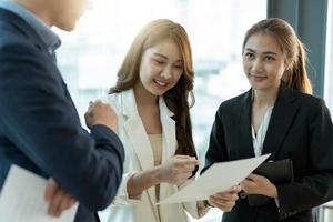 grupo de jóvenes y felices compañeros de equipo de personas corporativas asiáticas que se reúnen para discutir negocios en la oficina foto