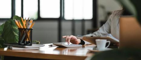 Close up of businesswomen or accountant using calculator calculate while working analytic business report on the workplace, Planning financial and accounting concept photo