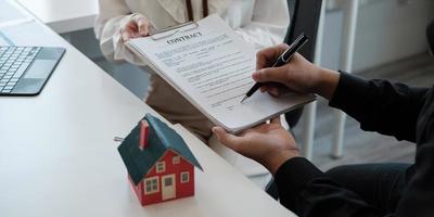 Real estate brokers point to a contract paper and advise customers to sign their names. customer sign agreement contract signature for buy or sell house. Real estate concept contact agreement concept photo