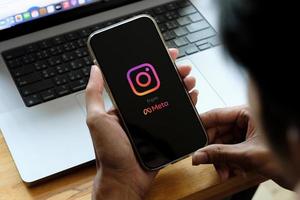 A man holds Apple iPhone 13 with Instagram application on the screen at cafe. Instagram from meta is a photo-sharing app for smartphones. photo