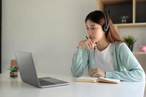 Happy young woman studying online, watching webinar, podcast on laptop. E-learning concept photo