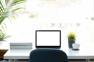 Mockup image of laptop computer with blank white screen on working space at home office photo