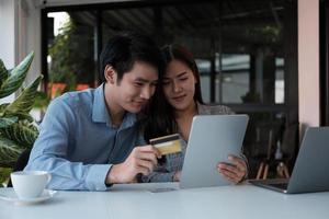 Asian couple at home shopping online with digital tablet and credit card photo