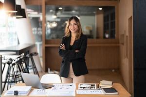 empresaria joven asiática, mujer de negocios con los brazos cruzados en el lugar de trabajo en su oficina foto