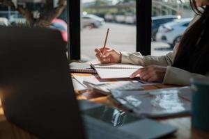 mano de mujer tomando notas en el bloc de notas. escritura. escritura creativa. negocio que trabaja para el cálculo de la contabilidad financiera en la oficina. foto