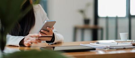 mujer joven con tarjeta de crédito y usando un teléfono inteligente para comprar en línea. concepto de compra de pago en línea. banner de espacio de copia foto