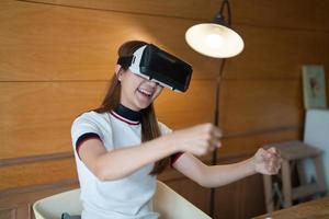 Excited young woman in VR goggles driving car in virtual reality. Lady screaming when turning virtual steering wheel, teen playing in racing computer game or road simulator, enjoying 3d gaming photo