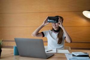 Young asian female in vr goggle attenting virtual working for financial at home photo