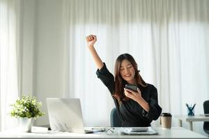 retrato de una joven y feliz mujer asiática de negocios celebrando el éxito con los brazos arriba. expresión positiva, éxito en el concepto de negocio foto