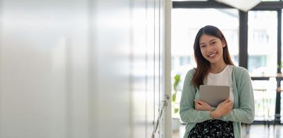retrato de joven feliz estudiante asiático atractivo sonriendo y mirando a la cámara. mujer asiática en auto educación futura o concepto de aprendizaje personalizado. bandera foto