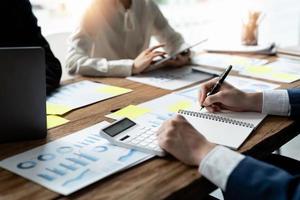 diverse businesspeople cooperate work together discussing company financial statistics, multiracial colleagues employees collaborate brainstorm with finance document at meeting photo