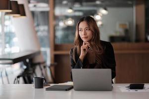 Asian beautiful woman thinking idea and working with laptop computer for financial in modern office photo