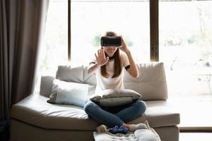 Concept of technology,gaming,entertainment and people.asian woman enjoying virtual reality glasses while relaxing in living room.Happy young guy with VR headset playing video game at home photo