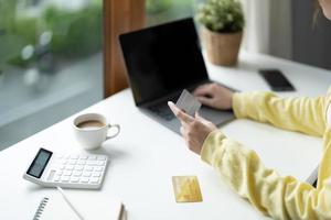 Close up of girl hold bank credit card and type on laptop, shopping online using computer, buying goods or ordering online, entering bank accounts and details in online banking offer photo