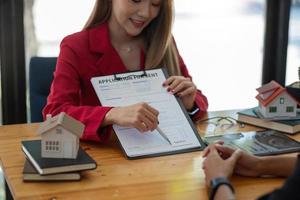 el cliente firma los documentos para hacer el contrato legalmente, las ventas de viviendas y el concepto inmobiliario de alquiler de viviendas foto