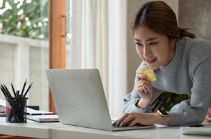 cierre la imagen de una mujer feliz sosteniendo una tarjeta de crédito mientras usa una computadora portátil. compras en línea con devolución de efectivo, ventas con descuento, precios bajos, ahorro de dinero. concepto de devolución de dinero. foto