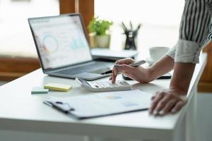 Close up Business woman using calculator and laptop for do math finance on wooden desk, tax, accounting, statistics and analytical research concept photo