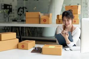 Portrait of Asian young woman SME working with a box at home the workplace. startup small business owner, small business entrepreneur SME or freelance business online and delivery concept photo