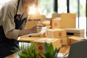 Startup SME small business entrepreneur SME or freelance Asian woman using a laptop with box, online marketing packaging box and delivery, SME concept photo