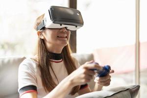 Concept of technology,gaming,entertainment and people.asian woman enjoying virtual reality glasses while relaxing in living room.Happy young guy with VR headset playing video game at home photo