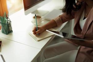 Cropped photo of woman writing making list taking notes in notepad working or learning on laptop indoors- educational course or training, seminar, education online concept