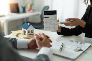 Real estate agent showing financial rate home loan for sign agreement customer the contract legally, Home sales and home insurance concept. photo