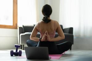 joven yogui practicando yoga, sentada en una pose de vajrasana con namaste detrás de la espalda, ejercitándose con ropa deportiva rosa. foto
