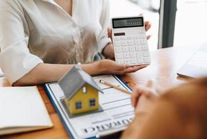 Real estate agent or bank officer describes the loan interest to the customer with home purchase contracts or on office loans and interest rates. photo